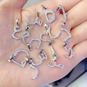 Macro shot of silver Arabic letter pendants with sparkling clear zircon stones