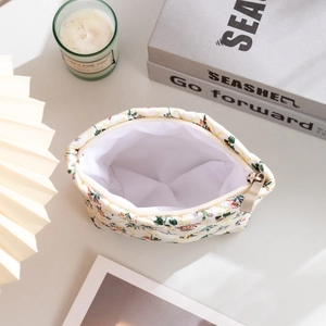 Top view of floral quilted toiletry bag with zipper and ivory fabric on a lifestyle desk