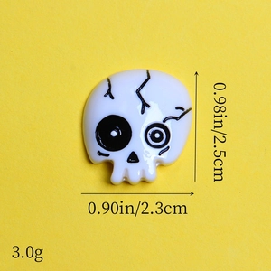 Detailed view of resin skull charm with dimensions 2.5cm height and 2.3cm width on yellow backdrop