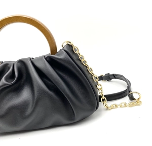 Detail of black cloud bag with pleated leather, round wooden handle and gold chain