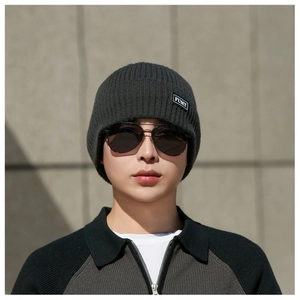 Detail view of dark grey ribbed knit beanie featuring a stitched FUMY logo patch