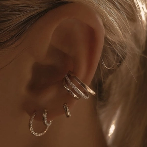 Close-up of stacked 18K rose gold ear cuffs and hoop earrings with pavé zircon stones