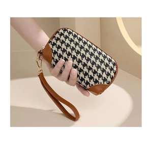 Detail of elegant houndstooth clutch with brown leather trim and golden wristlet buckle