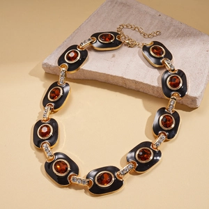Détail macro de pierres en résine ambrée avec cristaux sur un collier à maillons dorés
