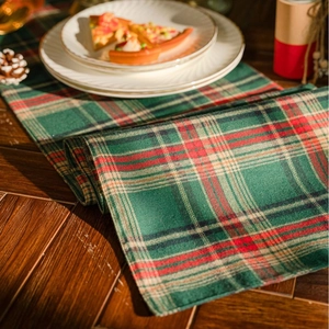 Classic red and green plaid table runner with rustic cotton texture on wooden surface