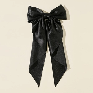 Detail of elegant black satin oversized bow hair clip with long silk streamers