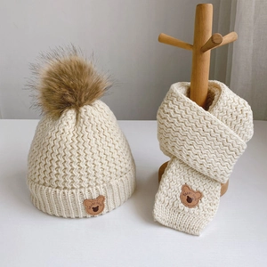 Cozy cream knitted hat and scarf set for toddlers featuring cute brown pom pom and bear labels