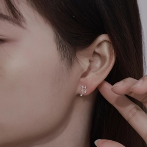 Close-up of a sterling silver constellation stud earring with sparkling crystals on ear