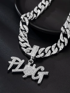 Macro shot of silver hip hop necklace with iced-out PLUG pendant on black base