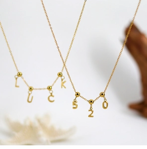 Close-up of gold DIY LUCKY and 520 pendants with adjustable chain on wooden stand