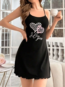 Detail view of black slip nightgown featuring pink heart print and ruffled hemline