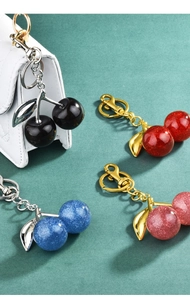 Detail of four colorful cherry keychains in resin with glitter and metal clasps