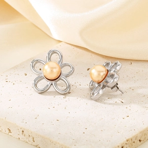 Close-up of flower earrings with zircon pearls on beige stone and silk background