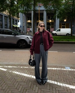 Detail of burgundy zip-up jacket paired with grey wide-leg trousers in a street setting