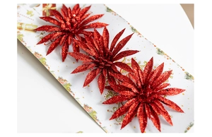 Close-up of three sparkling red glitter poinsettia flowers for Christmas tree decoration