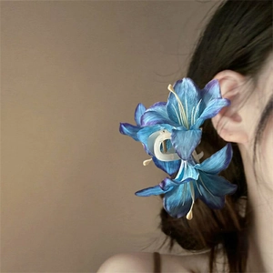 Detail of blue lily flower hair claw clip on white base worn on a woman's hair