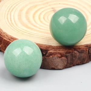 Detailed view of polished green aventurine crystal spheres on natural wood slice