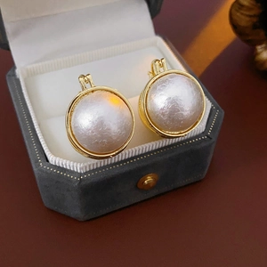 Gros plan de boucles d'oreilles perles vintage dans un écrin octogonal en velours gris