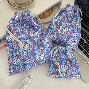 Three-piece floral cotton drawstring storage pouches in various sizes on a white desk