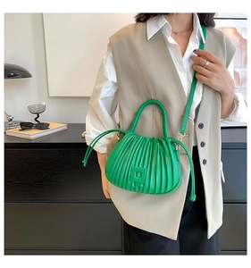 Detail view of bright green pleated bucket bag with round handle and drawstring accents