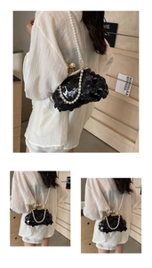 Detail of black sequined evening clutch bag with pearl shoulder strap and metal frame