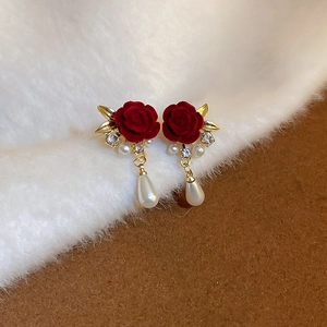 Dettaglio degli orecchini a rosa rossa in velluto con strass e ciondoli di perle