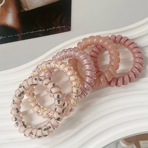 Detailed view of five colorful elastic telephone wire hair ties with heart and flower patterns
