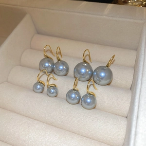 Detail view of four pairs of grey pearl drop earrings on beige velvet jewelry tray