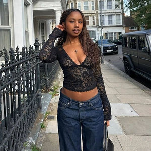 Streetstyle-Foto einer Frau in einem schwarzen Spitzenoberteil mit V-Ausschnitt und Jeans