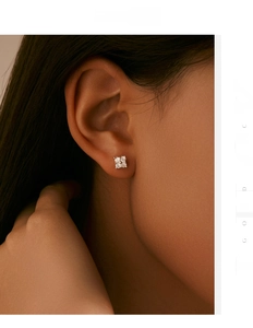 Close-up of minimalist silver four-petal flower stud earrings with sparkling diamonds