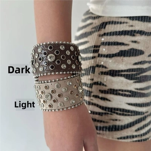 Close-up of wide leather bracelets with studded rhinestones in dark and light colors
