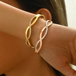 Close-up of gold and rose gold infinity C-shaped bracelets with rhinestones on wrist