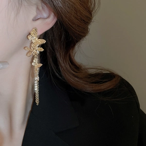 Detailed view of gold butterfly tassel earrings with zircon studs on a female model