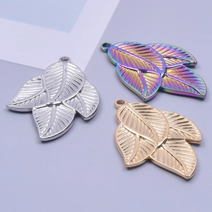 Detailed view of three leaf-shaped pendants in silver, gold and iridescent 18k plating