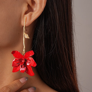 Detail of elegant gold branch earring with vibrant red flower pendant on a model
