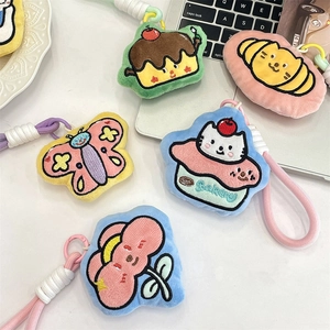Macro detail of plush cartoon charms with colorful embroidery and woven rope handles