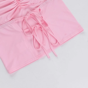 Detail of pink halter top showing stitching and crisscross lacing on smooth knit fabric
