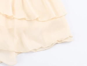 Dettaglio di balze in chiffon a strati con cuciture fini su un abito midi color albicocca