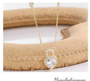 Detail view of gold heart lock pendant necklace with micro-inlaid white zircon stones