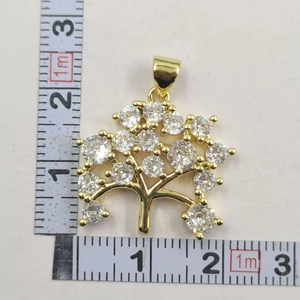 Close-up of golden Tree of Life pendant with zircon stones and ruler for size measurement