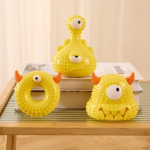 Detailed view of yellow monster-themed rubber dog chew toys with textured cleaning nubs