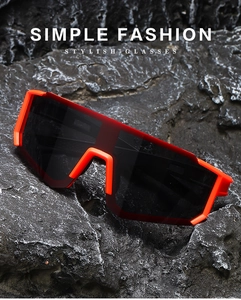 Detail of colorful sports sunglasses with orange frame on a textured rock background