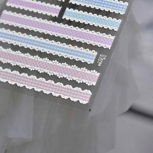 Close-up of 3D embossed nail stickers featuring lace edges and plaid patterns in blue and purple