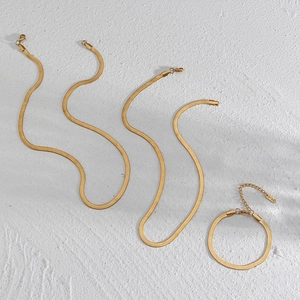 Flat lay of minimalist 18K gold plated stainless steel snake chain necklaces and bracelet