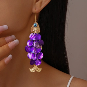 Detail of fish-shaped earring with purple shell scales and blue evil eye accent