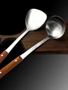 Détail d'une spatule et d'une louche en acier inoxydable avec manches en bois isolants