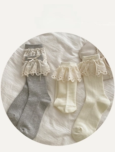 Detailed view of grey and cream cotton socks with lace trim and ribbon bows