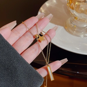 Minimalist gold titanium necklace with star and rectangular pendant shown in hand