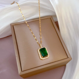 Luxuriöse Goldkette mit smaragdgrünem Anhänger und Kristallen auf Seidenhintergrund
