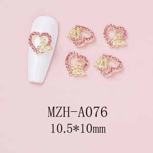Macro detail of heart-shaped nail art charm with pink crystal and golden bow design